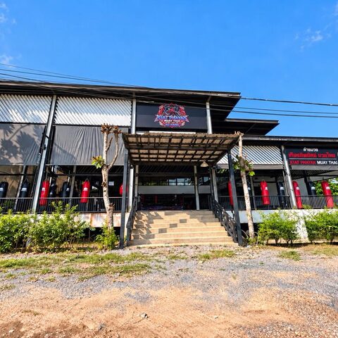 The Kiat Payak Muay Thai building: an open-air gym with heavy bags along the front and the tiger logo on the roof
