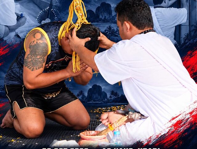 A trainer kneels as the mongkol headband is tied on during the opening ceremony