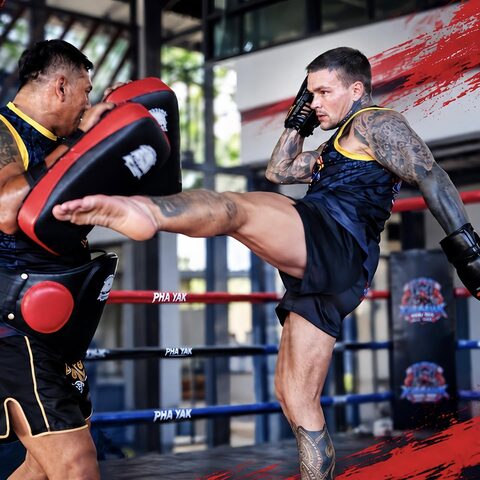 A student throws a teep on the pads with the red brush backdrop