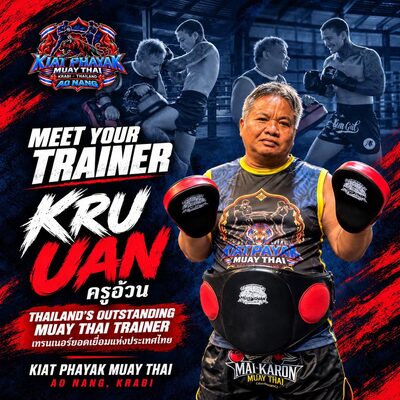 Kru Uan holding focus mitts and wearing a belly pad