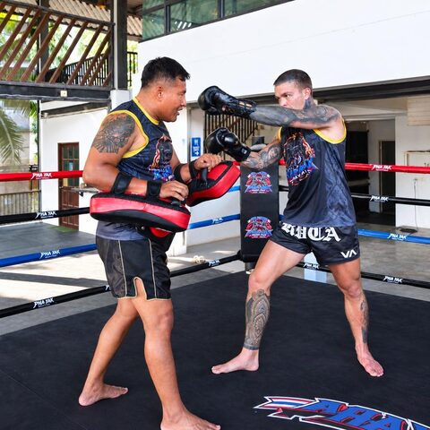 A trainer holds the pads while a student throws a cross in the ring
